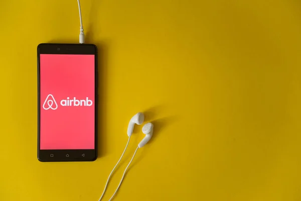 Logo de Airbnb en la pantalla del smartphone sobre fondo amarillo — Foto de Stock