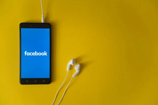 Логотип Facebook на экране смартфона на желтом фоне — стоковое фото
