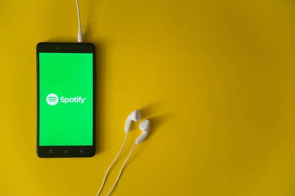 Spotify λογότυπο στην οθόνη του smartphone σε κίτρινο φόντο — Φωτογραφία Αρχείου
