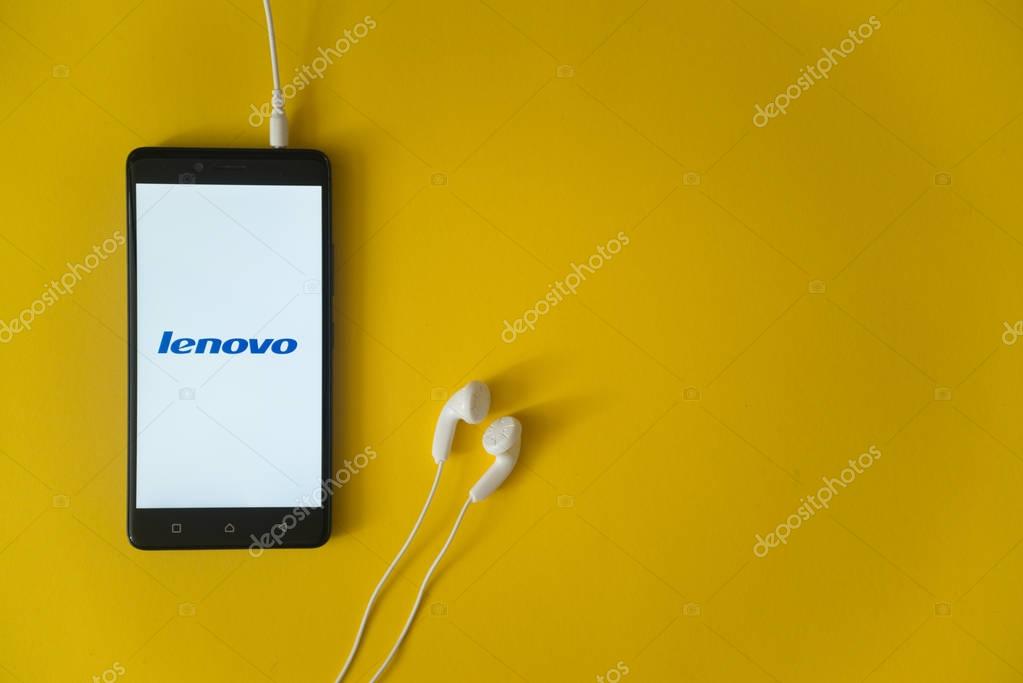 Los Angeles, USA, october 23, 2017: Lenovo logo on smartphone screen and earphones plugged in on yellow background.