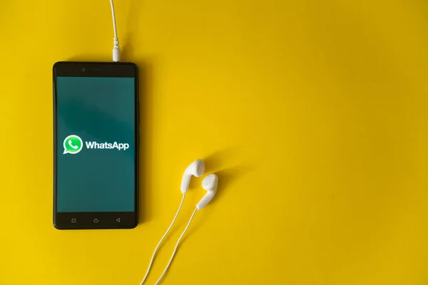 WhatsApp λογότυπο στην οθόνη του smartphone σε κίτρινο φόντο — Φωτογραφία Αρχείου