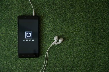 Uber logo üstünde smartphone perde yeşil çim zemin üzerine.