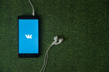 Vkontakte logo üstünde smartphone perde yeşil çim zemin üzerine.