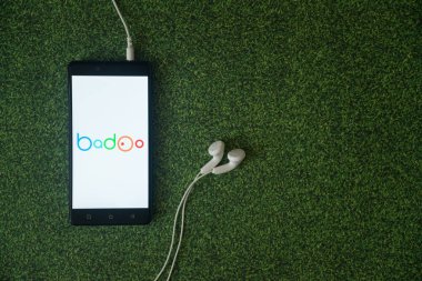 Badoo logo üstünde smartphone perde yeşil çim zemin üzerine.
