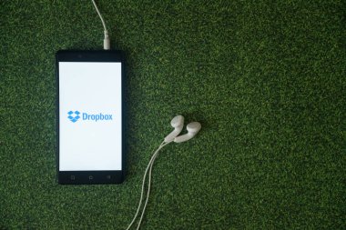 Dropbox logo üstünde smartphone perde yeşil çim zemin üzerine.