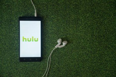 Hulu logo üstünde smartphone perde yeşil çim zemin üzerine.