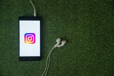 Instagram logo üstünde smartphone perde yeşil çim zemin üzerine.