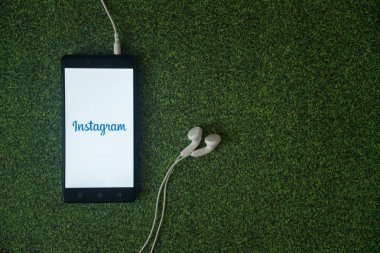 Instagram logo üstünde smartphone perde yeşil çim zemin üzerine.