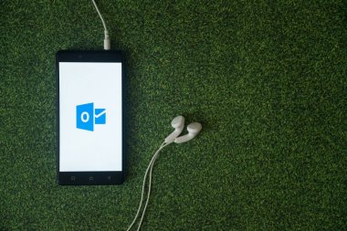 Microsoft office outlook logo üstünde smartphone perde yeşil çim zemin üzerine.