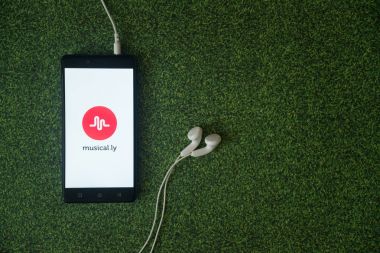 Musical.ly logo üstünde smartphone perde yeşil çim zemin üzerine.