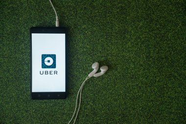 Uber logo üstünde smartphone perde yeşil çim zemin üzerine.