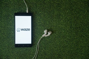 Waze logo üstünde smartphone perde yeşil çim zemin üzerine.