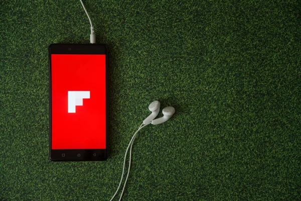 Flipboard logo na ekranie smartfona na tle zielonej trawie. — Zdjęcie stockowe