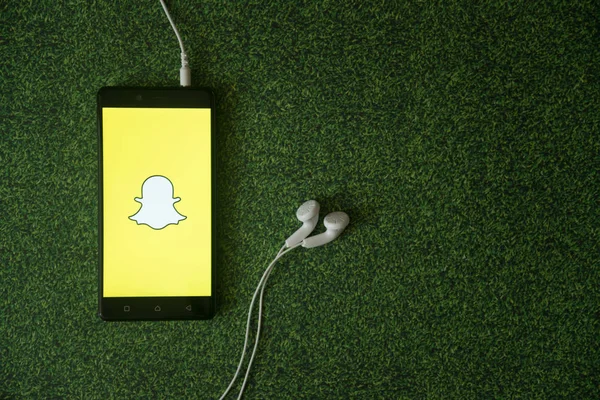 Snapchat logo üstünde smartphone perde yeşil çim zemin üzerine. — Stok fotoğraf