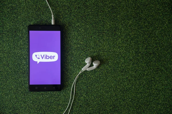 Viber logo na obrazovku smartphonu na zelené trávě pozadí. — Stock fotografie