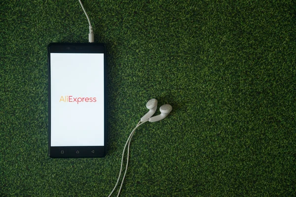 Логотип Aliexpress на экране смартфона на зеленом фоне травы . — стоковое фото