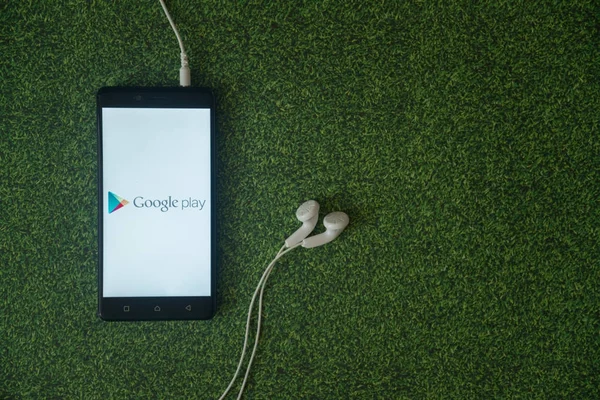 Google play logo on smartphone screen on green grass background. — Stock Photo, Image