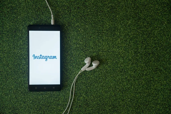 Instagram-Logo auf Smartphone-Bildschirm auf grünem Gras-Hintergrund. — Stockfoto