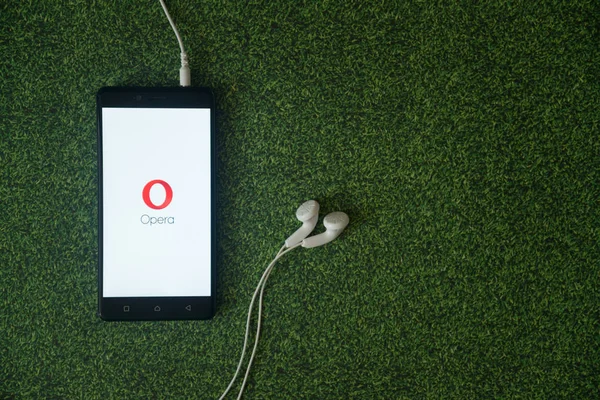 Opera mini logo sur l'écran du smartphone sur fond d'herbe verte . — Photo