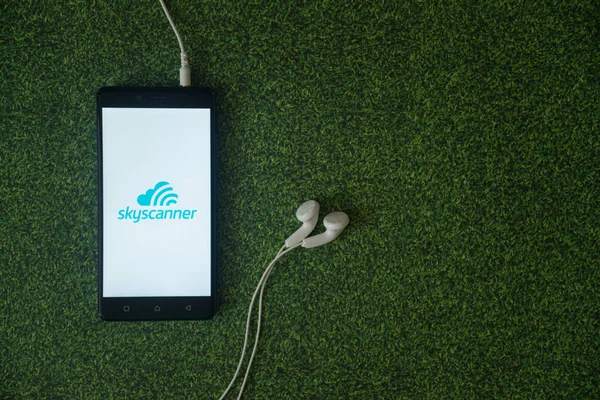 Logo Skyscanner sur l'écran du smartphone sur fond d'herbe verte . — Photo