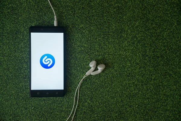 Shazam logo on smartphone screen on green grass background. — Stock Photo, Image