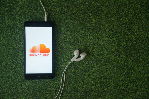 Soundcloud logo on smartphone screen on green grass background.