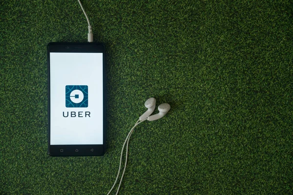 Logotipo de Uber en la pantalla del teléfono inteligente sobre fondo de hierba verde . — Foto de Stock