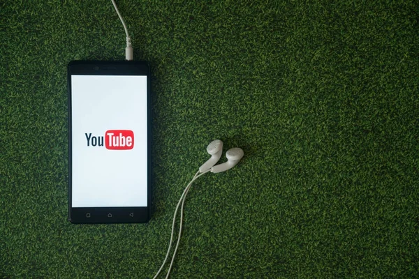 Youtube logo on smartphone screen on green grass background. — Stock Photo, Image