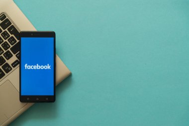Laptop klavye üzerinde yerleştirilen smartphone cep telefonu ile Facebook logosu.