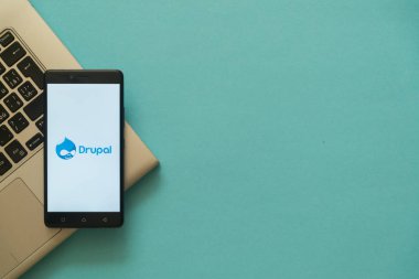 Drupal logo on smartphone placed on laptop keyboard. clipart