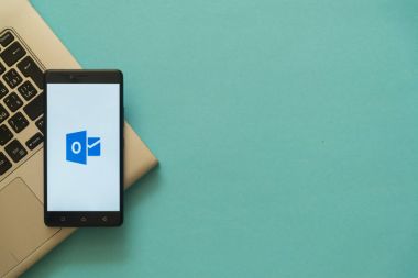 Microsoft office outlook logosu smartphone cep telefonu ile laptop klavye üzerinde yer.