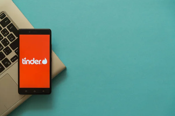 Tinder logo op smartphone geplaatst op laptop toetsenbord. — Stockfoto