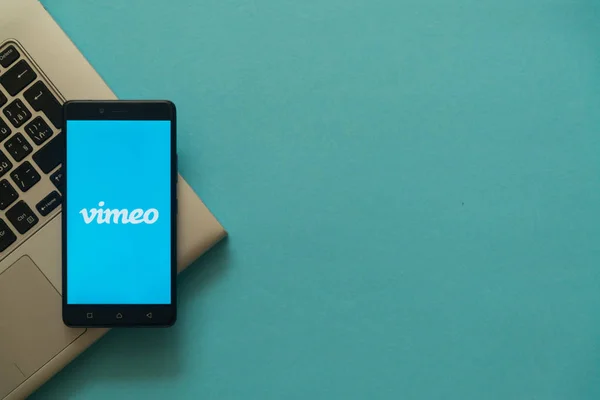 Logotipo de Vimeo en el teléfono inteligente colocado en el teclado portátil . — Foto de Stock