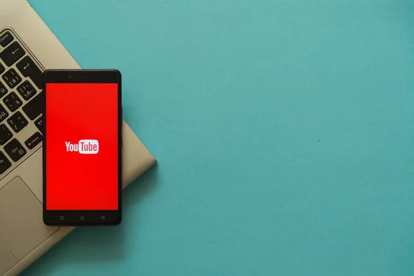 Logotipo do Youtube no smartphone colocado no teclado do laptop . — Fotografia de Stock