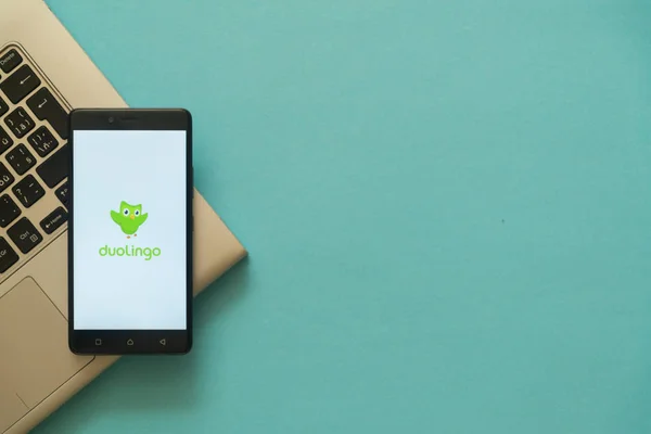 Logotipo de Duolingo en el teléfono inteligente colocado en el teclado portátil . — Foto de Stock