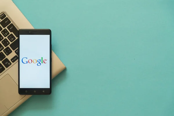 Logotipo de Google en el teléfono inteligente colocado en el teclado portátil . — Foto de Stock