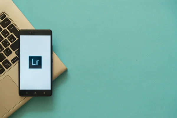 Adobe Photoshop Lightroom логотип на смартфоне размещен на клавиатуре ноутбука . — стоковое фото