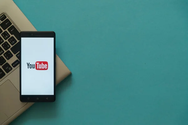 Logotipo do Youtube no smartphone colocado no teclado do laptop . — Fotografia de Stock