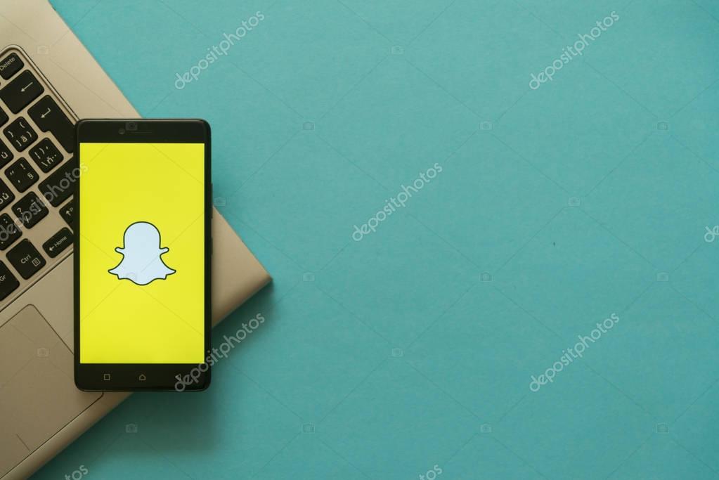 Los Angeles, USA, october 19, 2017: Snapchat logo on smartphone placed on laptop keyboard. Empty copyscape place on green background to write information.