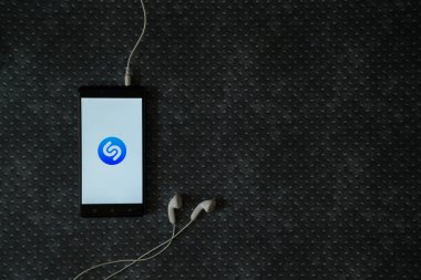 Shazam logo üstünde smartphone perde metal plaka arka plan üzerinde.