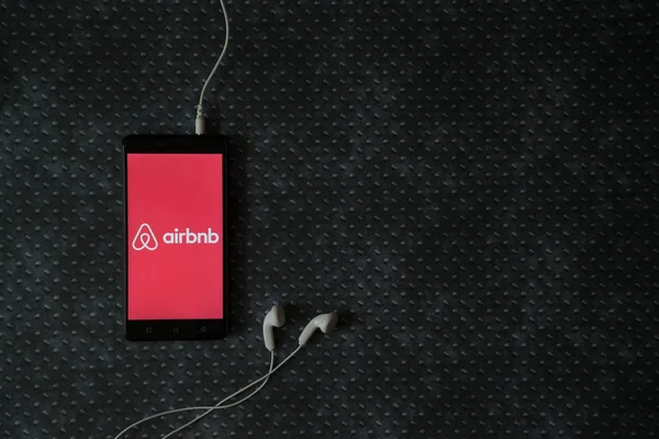 Logo de Airbnb en la pantalla del smartphone sobre fondo de placa metálica . — Foto de Stock