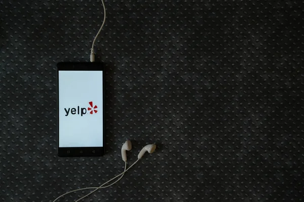 Logotipo Yelp en la pantalla del teléfono inteligente en el fondo de placa de metal . — Foto de Stock