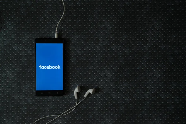 Logo de Facebook en la pantalla del teléfono inteligente sobre fondo de placa metálica . — Foto de Stock