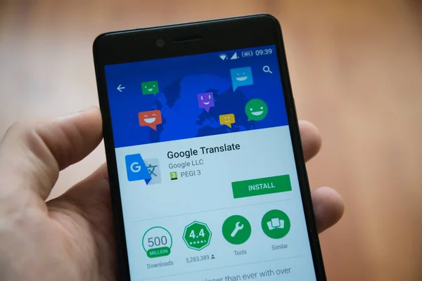 Hombre de la mano del teléfono inteligente con Google traducir aplicación en Google Play Store — Foto de Stock