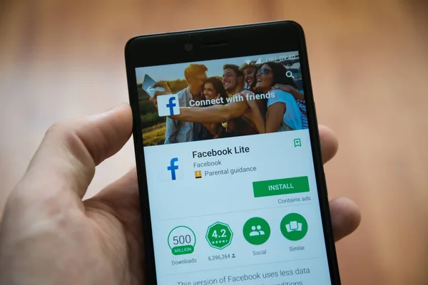 Ręką człowieka, trzymając smartfon z Facebook lite aplikacji w sklepie google play — Zdjęcie stockowe