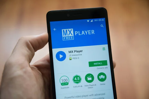 Мужчина держит в руках смартфон с приложением MX Player в магазине игр google — стоковое фото