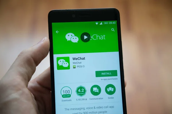 Hombre de la mano del teléfono inteligente con la aplicación WeChat en Google Play Store —  Fotos de Stock