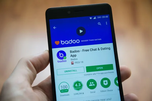Мужчина держит в руках смартфон с приложением Badoo в магазине игр google — стоковое фото