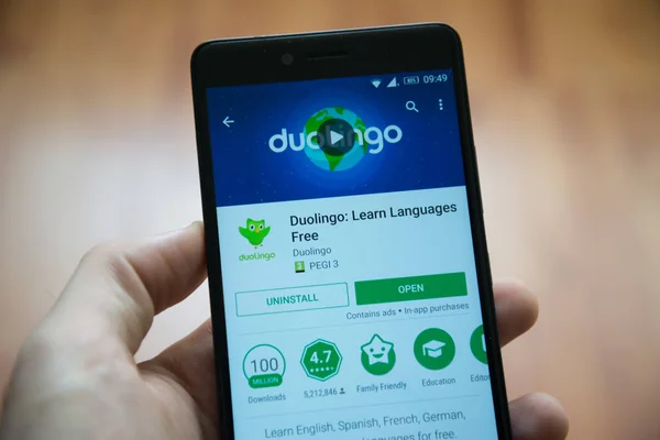 Мужчина держит в руках смартфон с приложением Duolingo в магазине игр google — стоковое фото