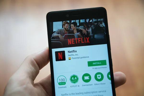 Hombre de mano sosteniendo el teléfono inteligente con aplicación Netflix en Google Play Store — Foto de Stock